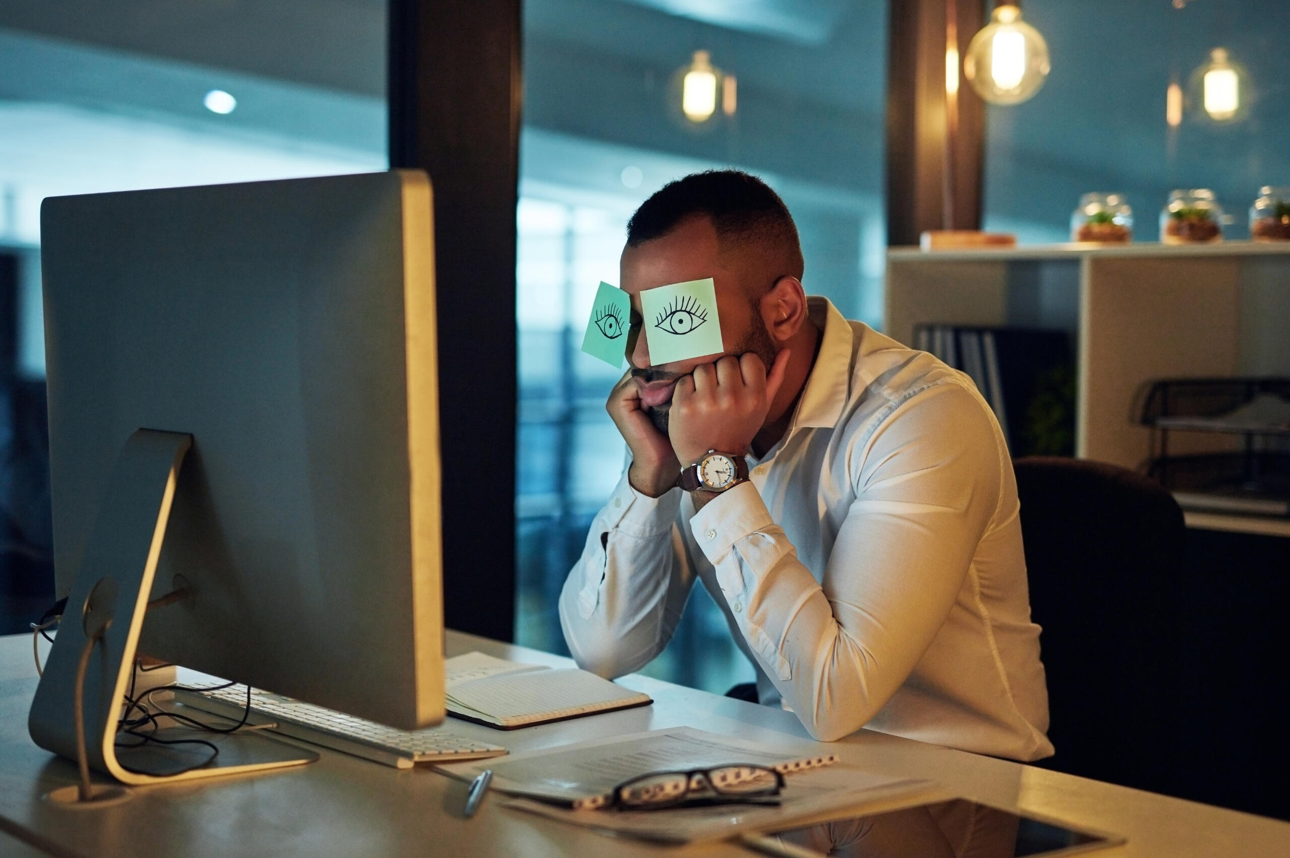 Man sitting at computer depressed with his eyes covered